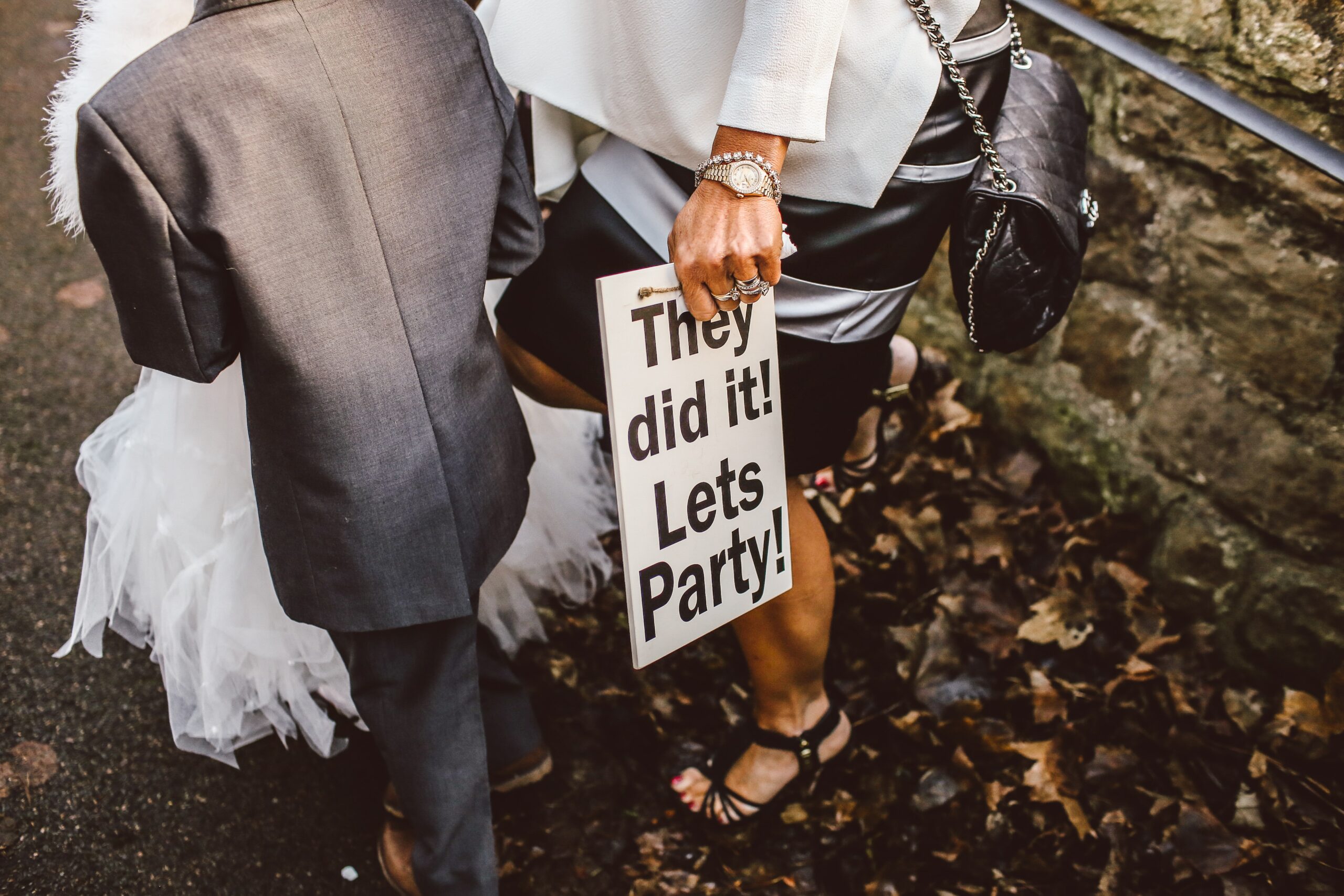 Brautpaar mit Schild „They did it – let’s party“